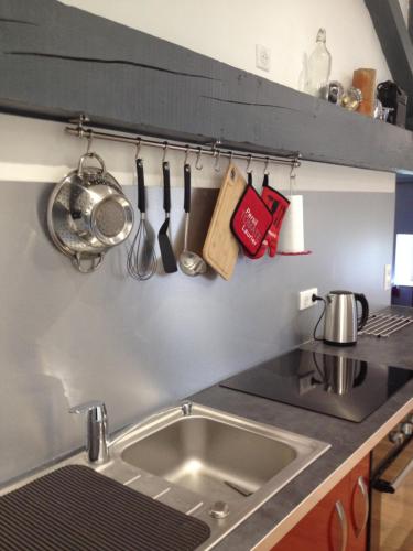a kitchen sink with utensils hanging on a wall at Le Cadran So'Lair in Saint-Germain-lʼHerm