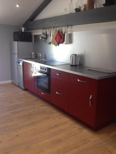 - une cuisine avec des placards rouges et une cuisinière dans l'établissement Le Cadran So'Lair, à Saint-Germain-lʼHerm