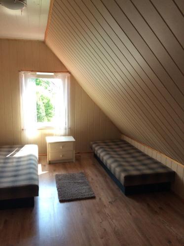 a attic room with two beds and a window at Domek letniskowy Wczasowik 2 in Kruklanki