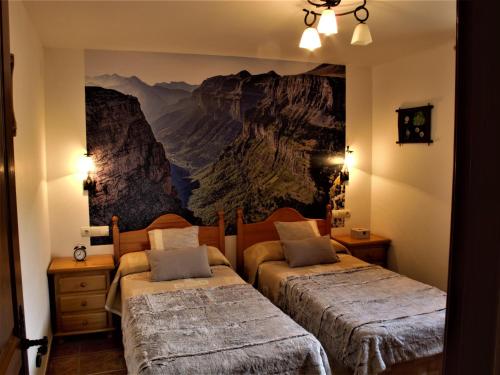 een slaapkamer met 2 bedden en een schilderij aan de muur bij Casa Ortiz in Nerín
