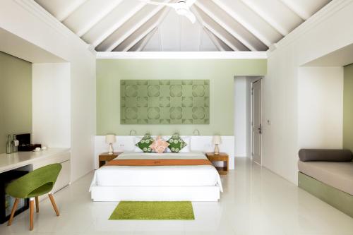 a bedroom with a bed and a couch at Sun Siyam Olhuveli in South Male Atoll