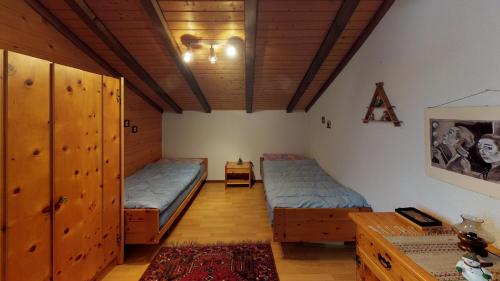 - une chambre avec 2 lits, des placards en bois et une table dans l'établissement Eieltini B EJB1, à Blatten bei Naters