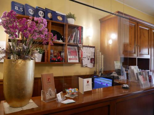 a desk with a vase with purple flowers on it at Locanda San Paolo in Monza
