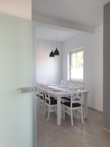 a white dining room with a white table and chairs at Pokoje u Jasia i Małgosi in Skawa