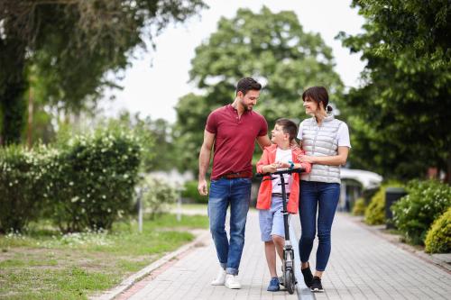 a family walking down a sidewalk with a child on a bike at Barack Thermal & Natura Apartments in Tiszakécske