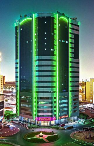 a large building with green lights on it at Alain Hotel Ajman in Ajman 