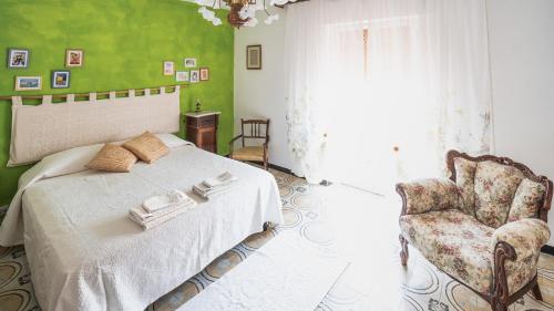 ein grünes Schlafzimmer mit einem Bett und einem Stuhl in der Unterkunft Su 'e Torigheddu - Casa con terrazza panoramica in Cuglieri