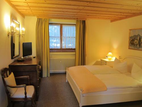 Schlafzimmer mit einem Bett, einem Schreibtisch und einem TV in der Unterkunft Ferienwohnungen Elisabeth am See in Rottach-Egern