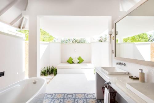 a white bathroom with a tub and a sink at Sun Siyam Olhuveli in South Male Atoll