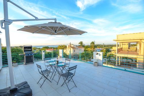 a patio with a table and chairs and an umbrella at Abiki Mauritius with Tourism Authority Permit in Albion