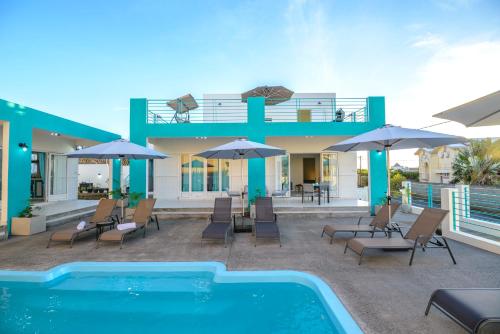 una casa con piscina, sillas y sombrillas en Abiki Mauritius en Albion