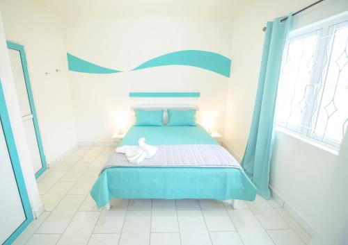 a bedroom with a bed with a blue bedspread at Abiki Mauritius with Tourism Authority Permit in Albion
