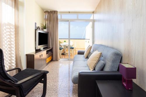 sala de estar con sofá azul y TV en Apartamentos Ohana - Edificio Tonillo, en Los Cristianos