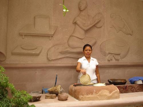 a woman standing in front of a stone sculpture at Hotel Maria Mixteca in Santa Cruz Huatulco