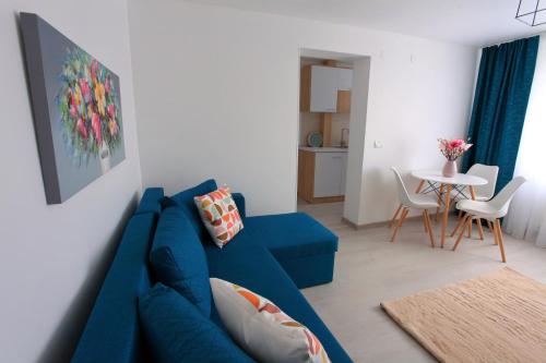 a living room with a blue couch and a table at Apartament Delora View in Bumbeşti-Jiu