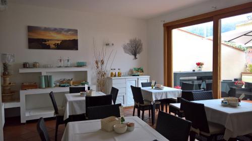 ein Restaurant mit weißen Tischen und Stühlen und einem Fenster in der Unterkunft Hotel Garibaldi in La Maddalena