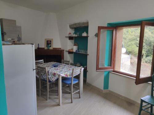 a kitchen with a table with chairs and a window at Sa Dommu 'e su coro in Triei
