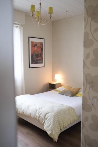 a bedroom with a large white bed and a chandelier at Pension de Kerioual in Roscoff