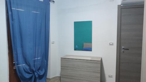 a bathroom with a blue shower curtain and a mirror at Sa Dommu 'e su coro in Triei