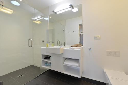 a white bathroom with a sink and a shower at Kerikeri Homestead Motel & Apartments in Kerikeri