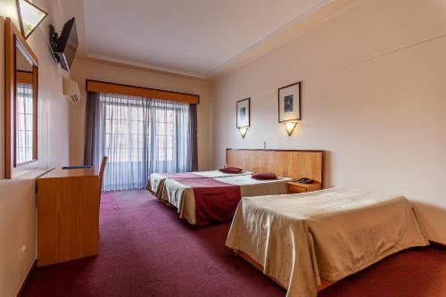 Cette chambre comprend 2 lits et une fenêtre. dans l'établissement Residencial Horizonte, à Lisbonne