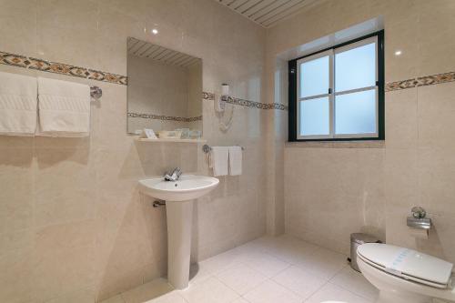 La salle de bains est pourvue d'un lavabo, de toilettes et d'une fenêtre. dans l'établissement Residencial Horizonte, à Lisbonne