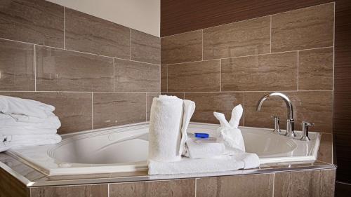 ein Badezimmer mit einer Badewanne, Handtüchern und einem Waschbecken in der Unterkunft Best Western Plus Fergus Hotel in Fergus
