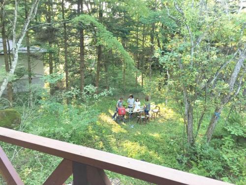 a group of people sitting at a table in the woods at Guest house Japan Kita-Karuizawa in Saikubo