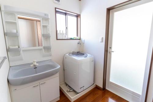 a white bathroom with a sink and a mirror at Guest house Japan Kita-Karuizawa in Saikubo