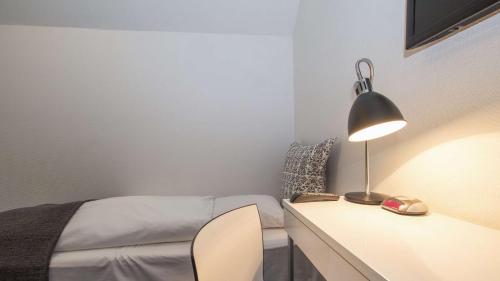 a bedroom with a bed and a desk with a lamp at Best Western Hotel Herman Bang in Frederikshavn