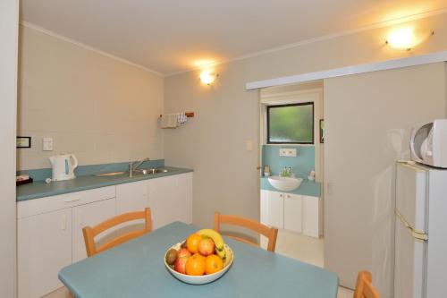 a kitchen with a bowl of fruit on a table at Kerikeri Homestead Motel & Apartments in Kerikeri