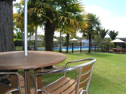 a wooden table and chairs sitting next to a pool at Kerikeri Homestead Motel & Apartments in Kerikeri