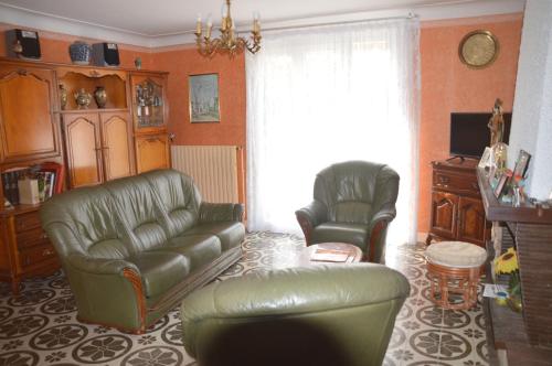 a living room with a leather couch and two chairs at VILLA AUX PIEDS DES PYRENEES in Azereix