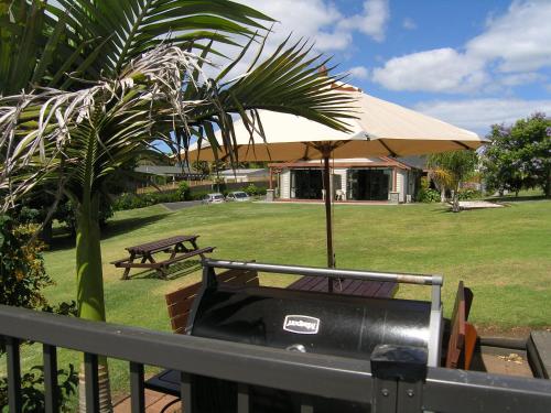 a grill with an umbrella and a picnic table at Kerikeri Homestead Motel & Apartments in Kerikeri