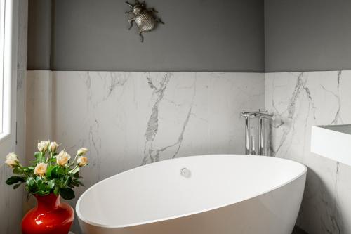 een badkamer met een wit bad en een vaas met bloemen bij L'8 Boutique Design Apartments in Bologna