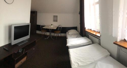 a room with two beds and a flat screen tv at Hotel Gryf in Gryfice
