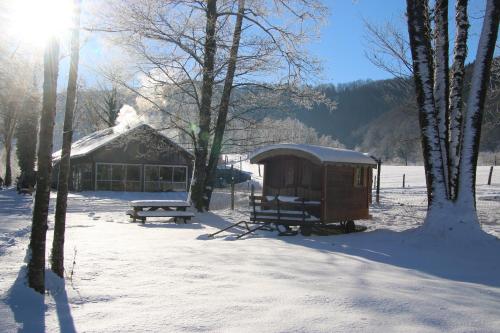 a building in the snow with a picnic table and a bench at Parc animalier du Hérisson in Doucier