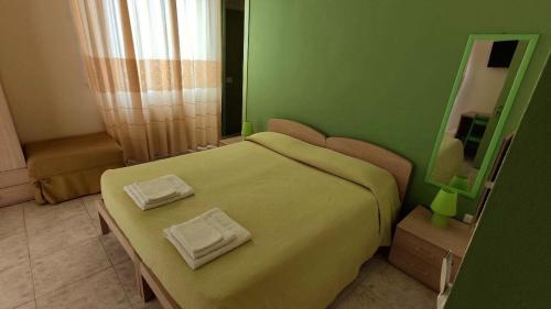 a green bedroom with a bed with two towels on it at Coral Rubrum in Alghero