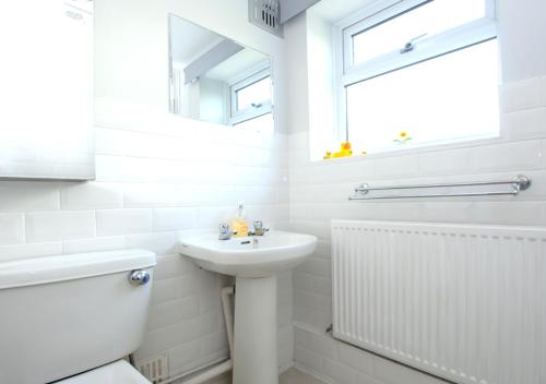a white bathroom with a sink and a mirror at Lifeboat Cottage in Deal