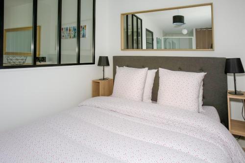 1 dormitorio con cama blanca y espejo en CITE D'ALETH - Au pied des plages & des ports en Saint-Malo