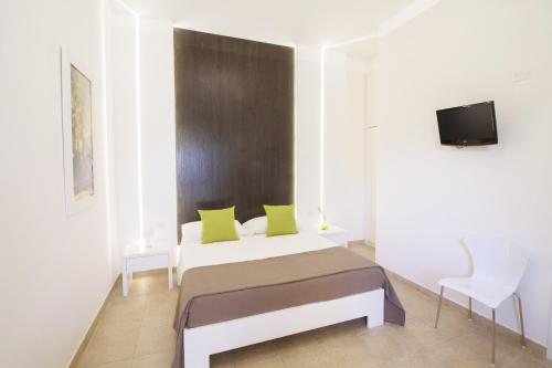 a bedroom with a bed with green pillows and a tv at La Casina Di Borgagne in Borgagne