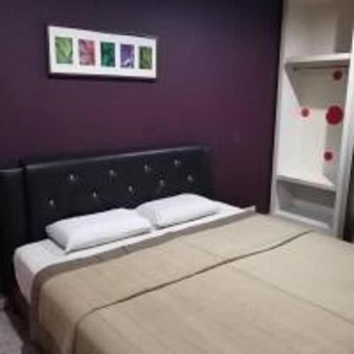 伯恩倉的住宿－Emerald Inn，卧室内的一张床位,带紫色墙壁