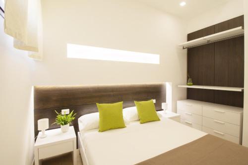 a bedroom with a white bed with two green pillows at La Casina Di Borgagne in Borgagne