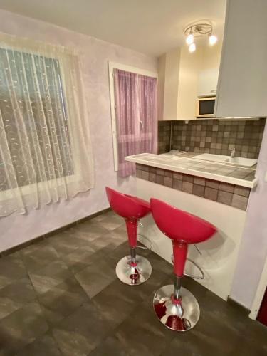 une cuisine avec deux tabourets rouges devant un comptoir dans l'établissement Les Gîtes, à Jausiers