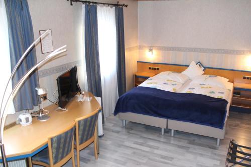 a bedroom with a bed and a desk with a computer at Hotel Restaurant Post Italia in Albstadt