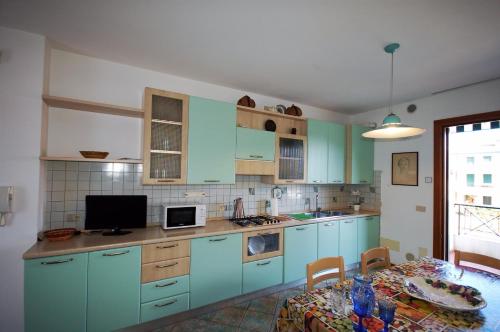 a kitchen with blue cabinets and a table with a dining room at Jolanda Vacanze in Cavallino-Treporti