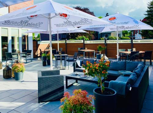 a patio with couches and tables and umbrellas at Hotel Stadt Aurich in Aurich