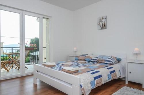 a white bedroom with a bed and a balcony at House Tina in Sveti Filip i Jakov