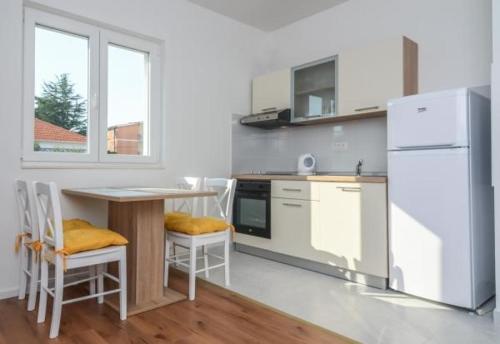 a kitchen with a table and a white refrigerator at House Tina in Sveti Filip i Jakov