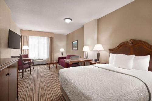 a hotel room with a bed and a living room at La Quinta by Wyndham Trinidad in Trinidad